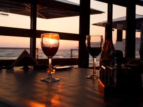 Wine glasses set for a seaside dinner at sunset