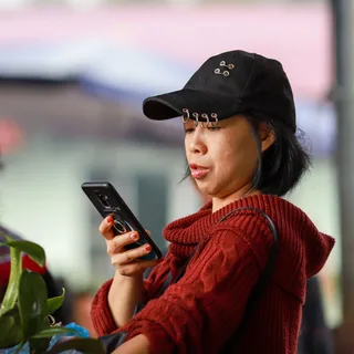 A young woman creating her profile on her phone in the sun